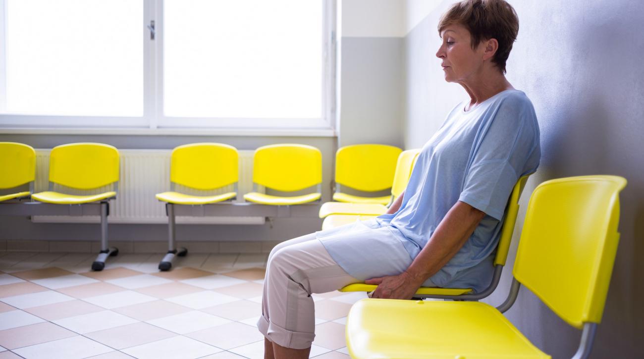 Woman sitting alone in waiting room, looking unhappy