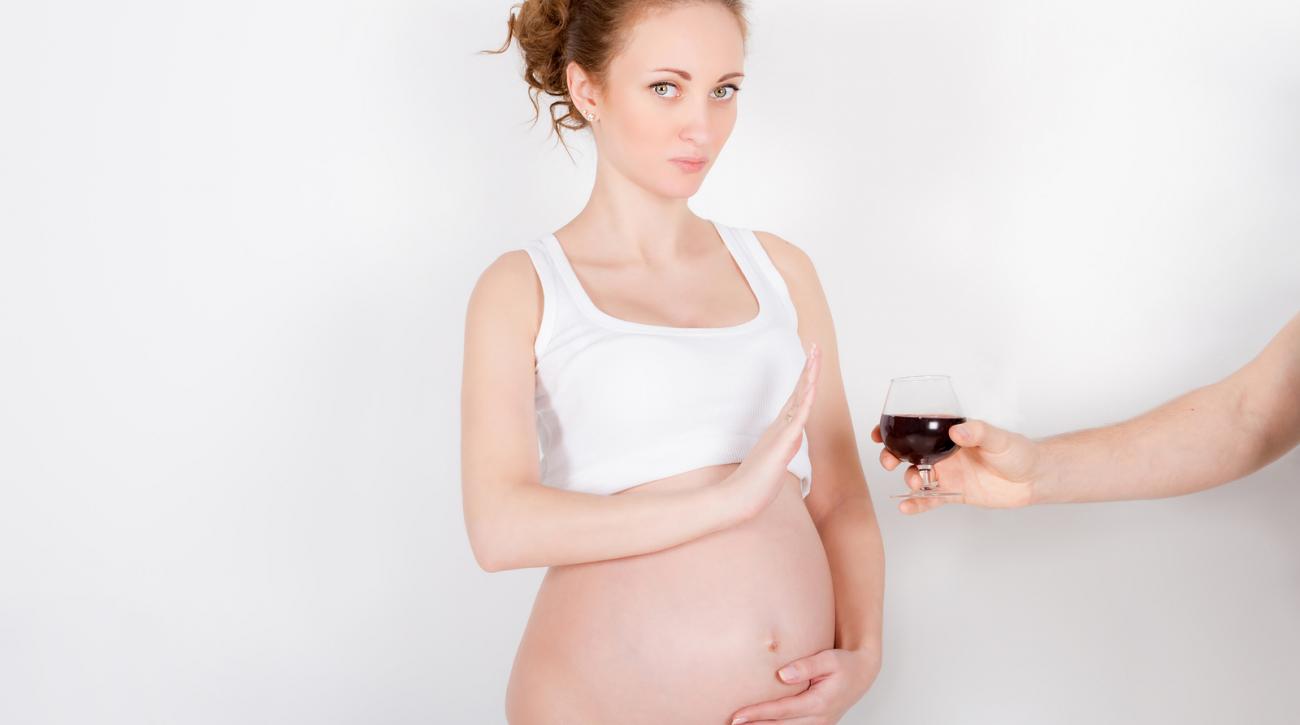 Pregnant woman pushes away glass of wine being offered