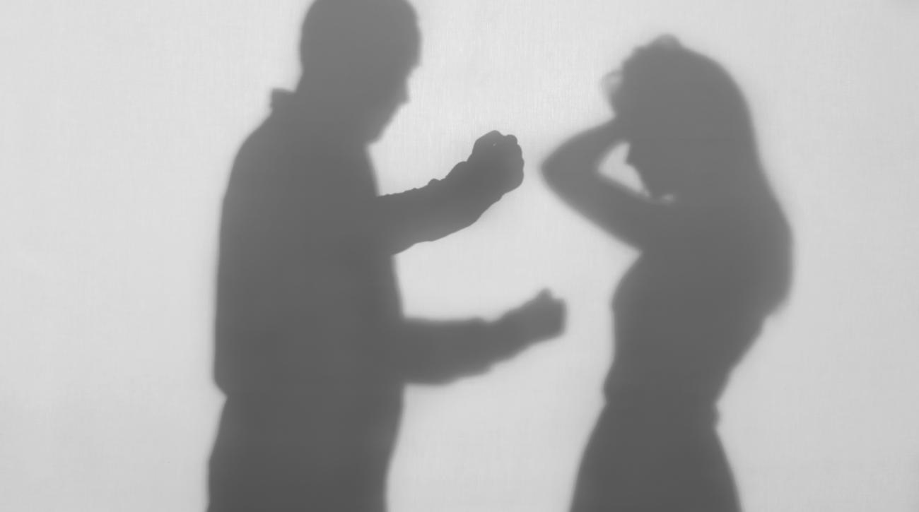 Silhouette of man with raised fist and woman holding hands to her head