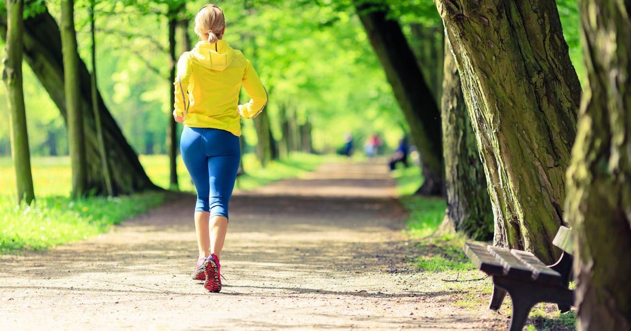Woman jogging on path surrounded by trees