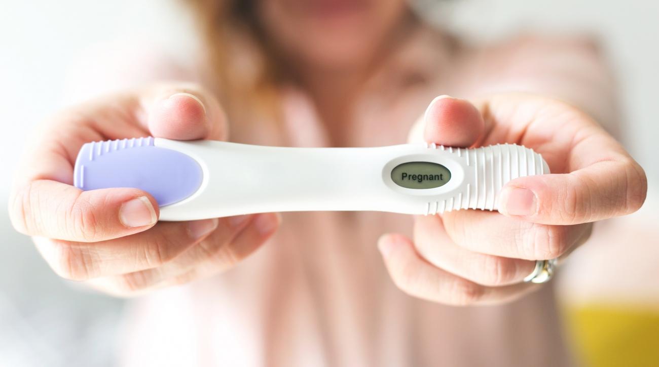 Woman holding out positive pregnancy test