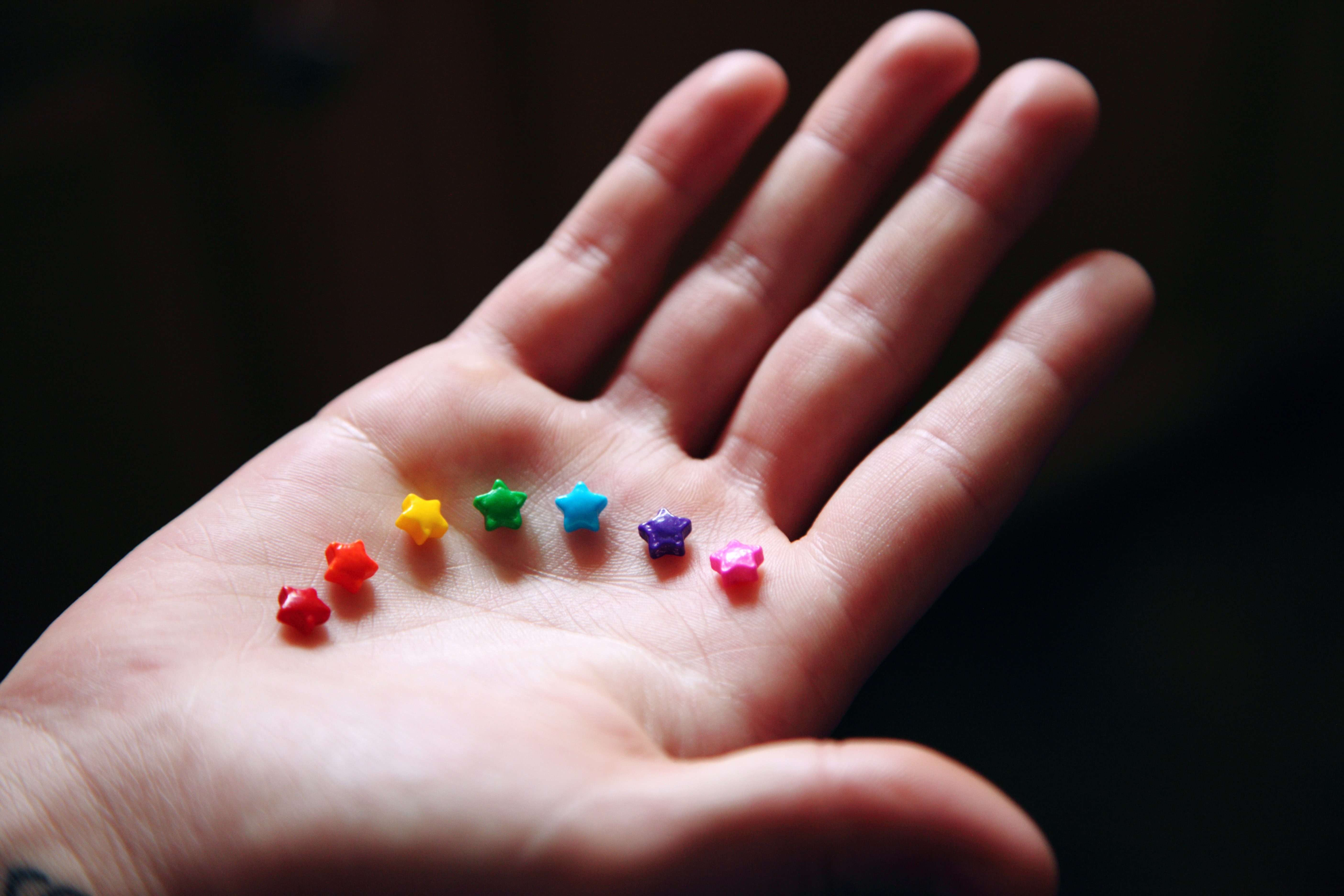 Photo by Sharon McCutheon at Unsplash: Rainbow candies in a white person's open palm
