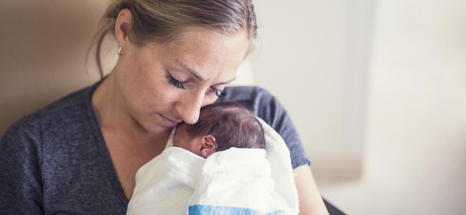 Woman holds newborn wrapped in blanket
