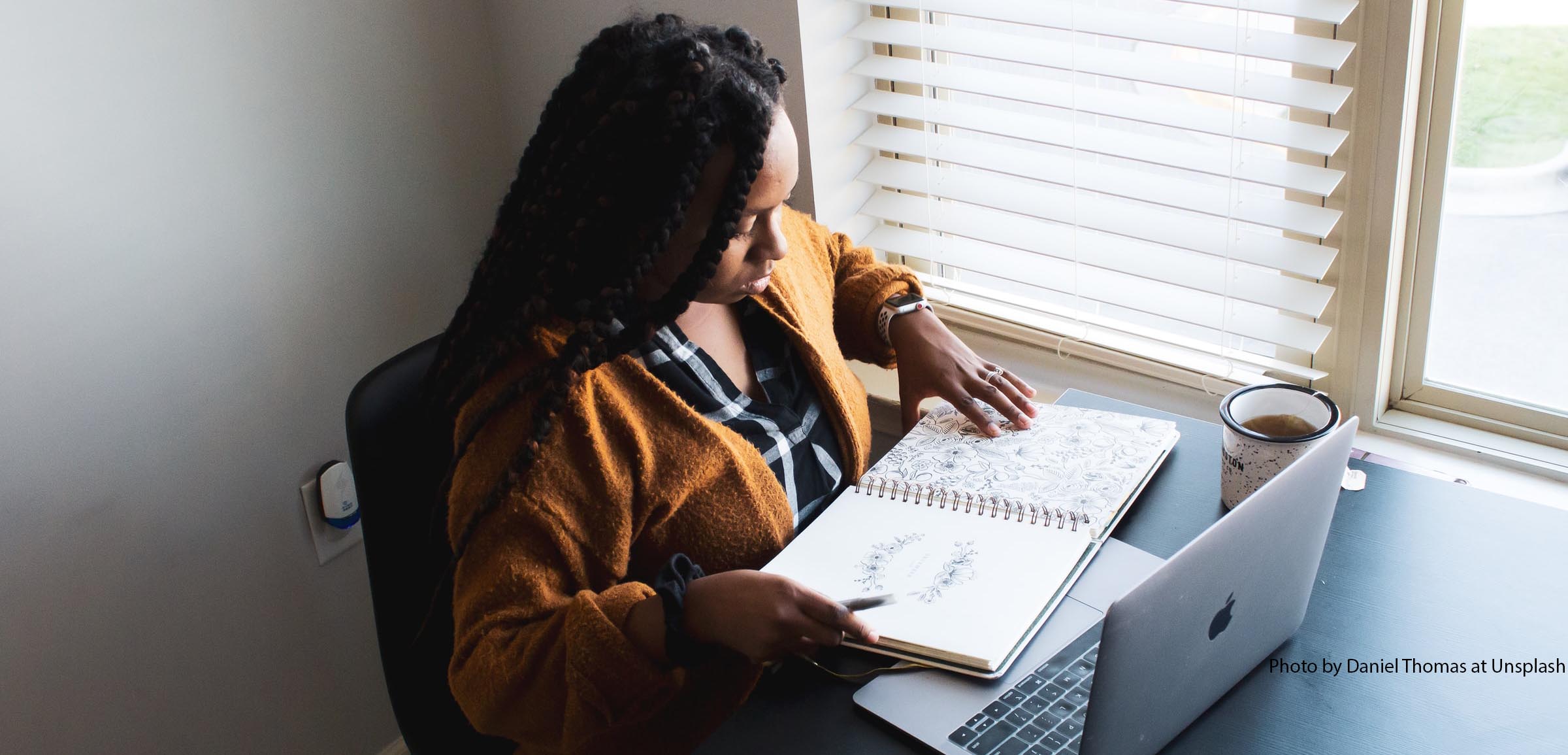 Black woman sitting at computer looking out window