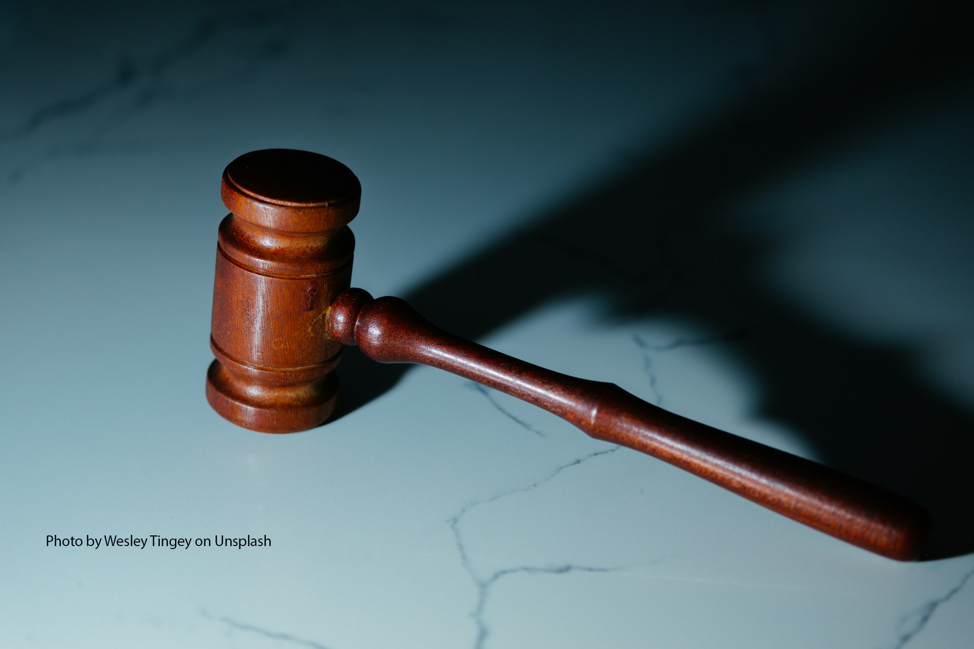 A wooden gavel rests on a white marble surface