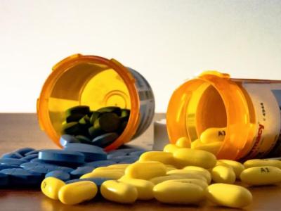 Blue and yellow pills spilling from prescription bottles