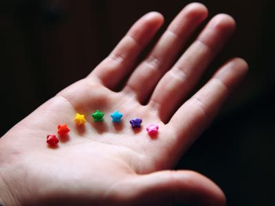 Photo by Sharon McCutheon at Unsplash: Rainbow candies in a white person's open palm