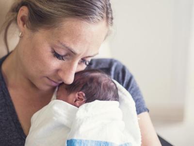 Woman holds newborn wrapped in blanket