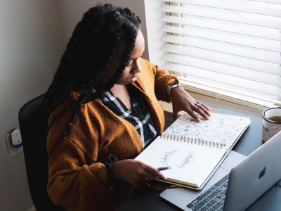 Black woman sitting at computer looking out window