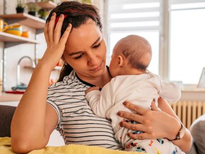 Woman holding baby and resting her head in her hand