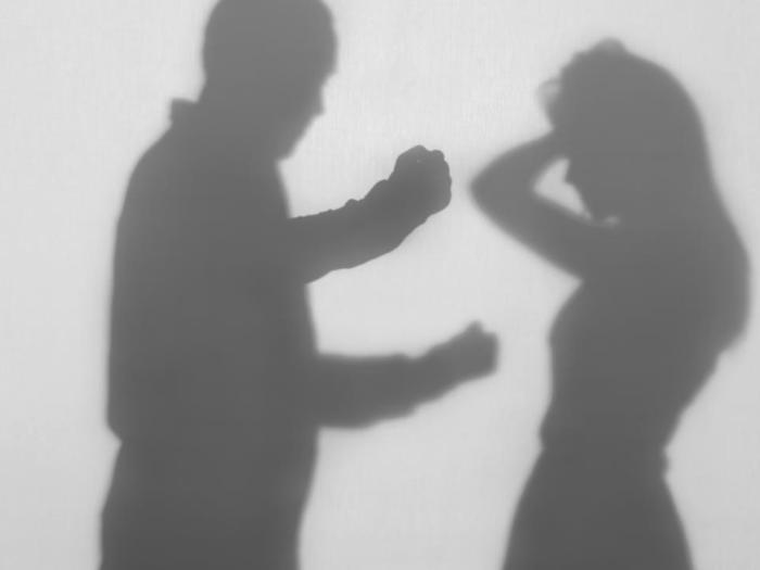 Silhouette of man with raised fist and woman holding hands to her head