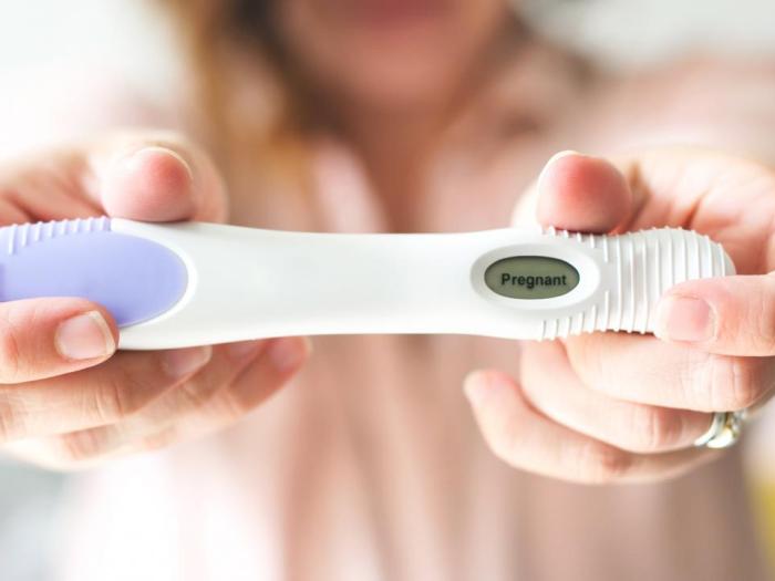 Woman holding out positive pregnancy test