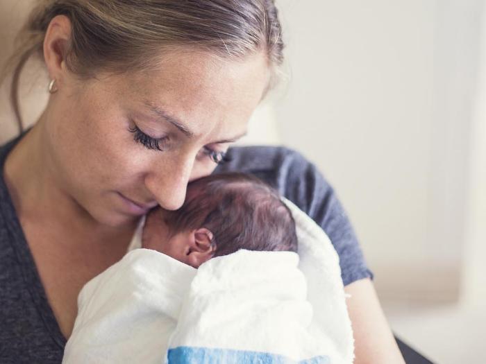 Woman holds newborn wrapped in blanket