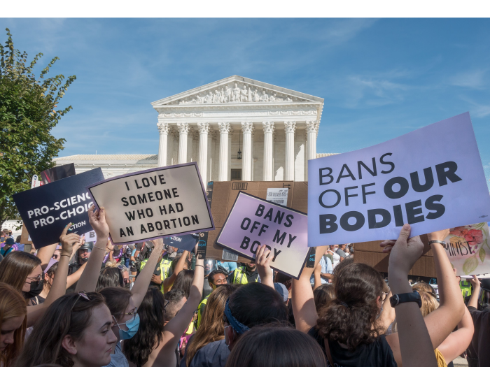 With the Supreme Court behind them, protestors hold signs reading "Bans off our bodies" and "I love someone who had an abortion"