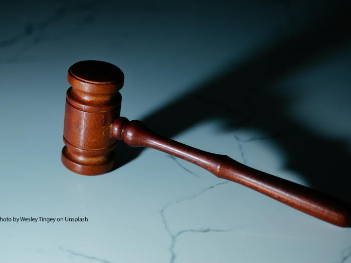 A wooden gavel rests on a white marble surface